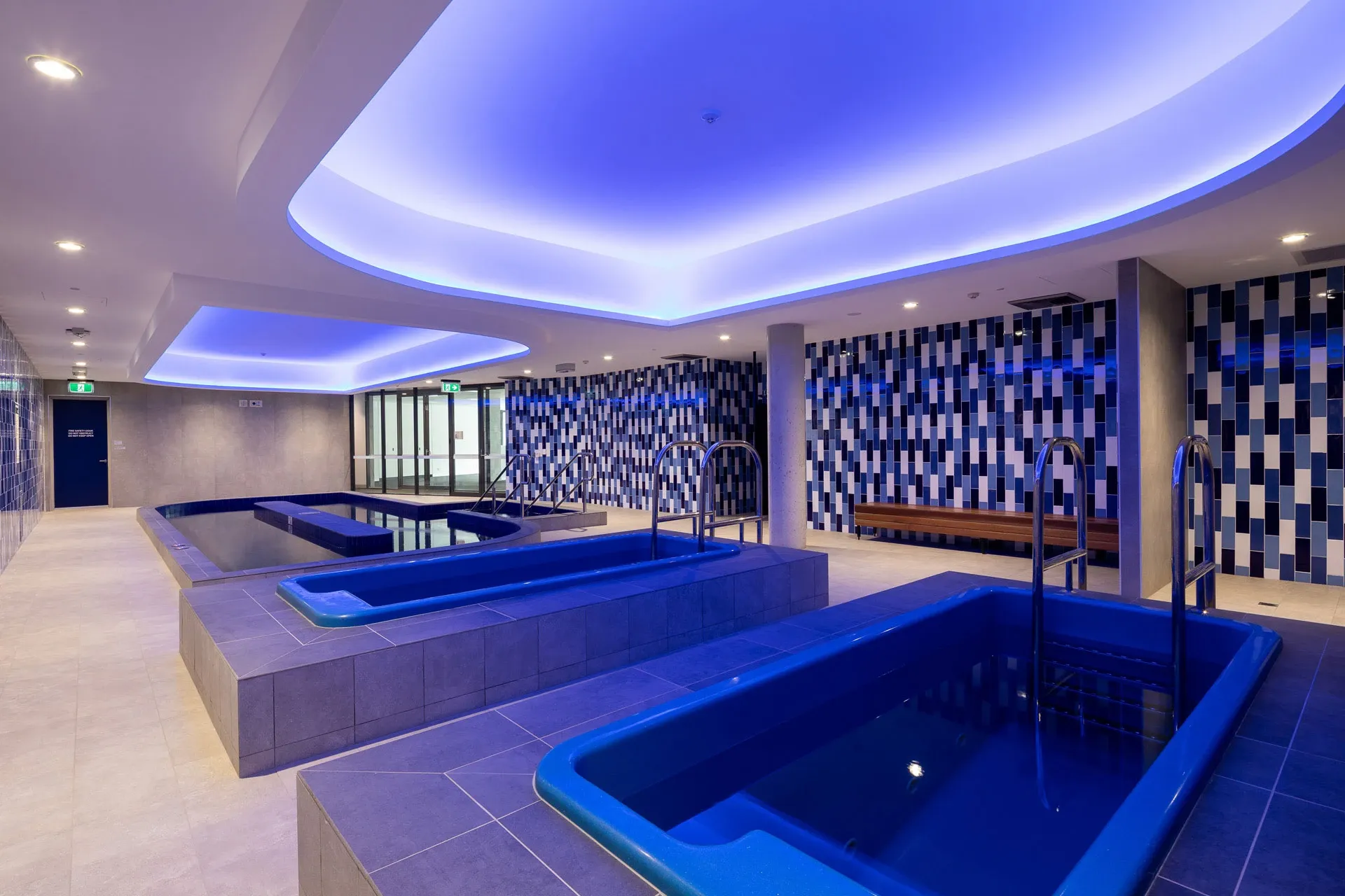 Commercial indoor hydrotherapy pools with stainless grab rails and tiled surrounds